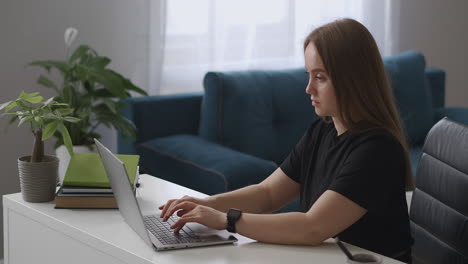 young-woman-dressed-black-t-shirt-is-chatting-in-social-nets-by-laptop-with-wireless-internet-connection-relaxing-at-home-at-weekends